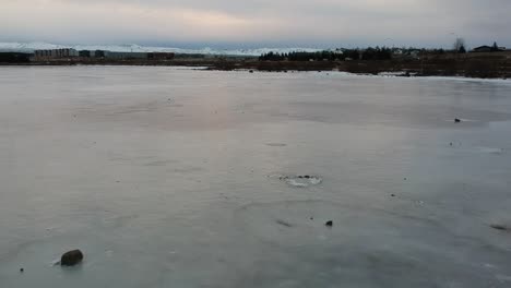 Low-flying-drone-shot-of-frozen-lake-Raudavatn,-near-Reykjavík,-Iceland