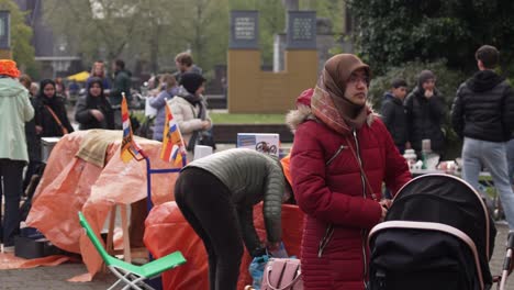 Young-mother-with-headscarf-and-pram-on-Dutch-King's-Day-market-Netherlands