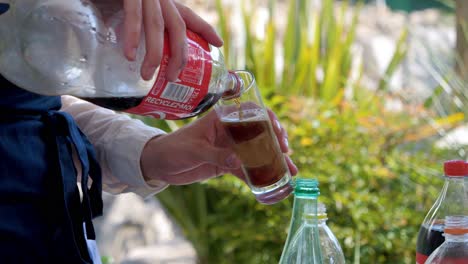 Waiter-pouring-soda-in-a-glass-for-people-sitting-in-outside-area-of-a-restaurant