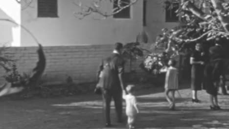 Man-Walks-with-a-Small-Children-in-the-Garden-of-an-Elegant-Home-of-1930s