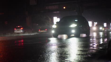 Slow-motion,-cars-driving-in-Wet-rainy-season-traffic,-road-at-night-illuminated-asphalted-road