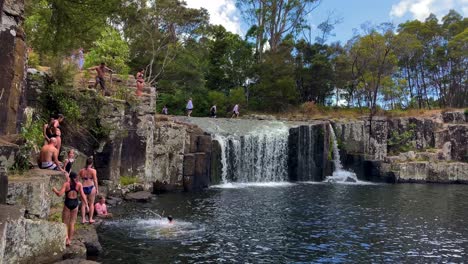 Kids-and-adults-jump-into-the-river-at-Charlie’s-waterfall-on-a-sunny-summer-day-in-New-Zealand