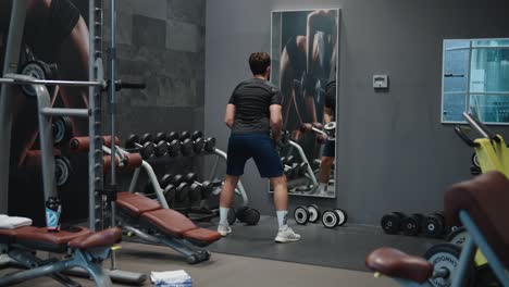 Solo-Un-Hombre-En-El-Gimnasio-Hace-Elevación-Lateral-Con-Pesas-Ejercicio-De-Hombro