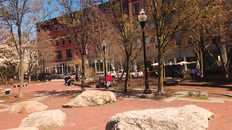 People-listening-to-street-muscian-in-Tommy-Park,-Portland,-Maine