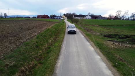 Coche-Saliendo-De-Una-Pequeña-Ciudad-Europea-Pasando-Por-Tierras-De-Cultivo