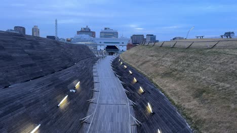 Pasarela-Elevada-De-Madera-Con-Luces-Al-Atardecer,-Arquitectura-Moderna,-Serena