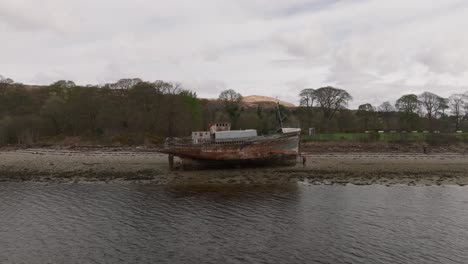 Aerial-orbiting-shot-of-tourists-walking-around-the-Corpach-Shipwreck-in-Scotland