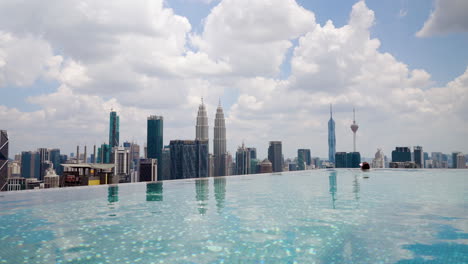 Woman-Swimming-In-Infinity-Pool-On-Hotel-Rooftop-With-View-Of-Kuala-Lumpur-City-Skyline-In-Daytime