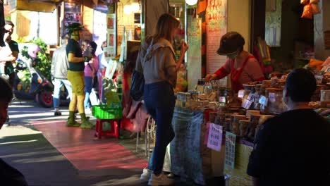 People-strolling-through-Jiufen's-old-street-lined-with-food-stalls,-souvenir-shops-and-gift-stores,-exploring-the-charming-mountain-village-town,-popular-tourist-attraction-of-Taiwan