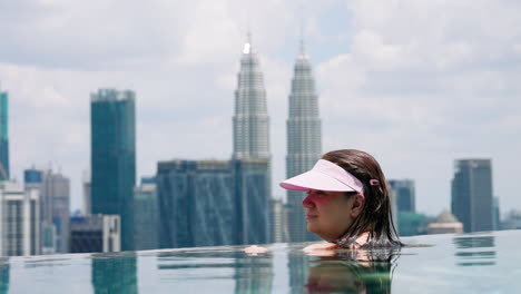 Woman-In-Rooftop-Infinity-Pool-With-Petronas-Twin-Towers-In-The-Background-In-Kuala-Lumpur,-Malaysia