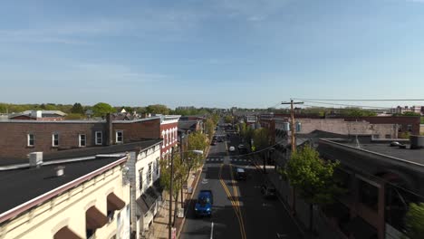 FPV-establishing-flight-over-small-american-town-with-main-street-on-driving-cars-between-historic-buildings-at-sunset