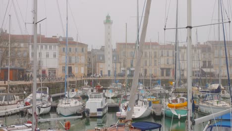 Misty-day-at-La-Rochelle-Old-Harbour-with-historic-Quai-Valin-lighthouse-among-moored-boats