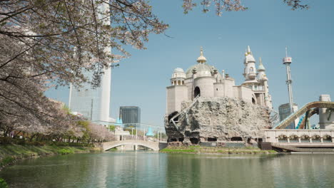 Seokchon-Lakefront-View-of-Lotte-World-Amusement-Park-and-Lotte-Tower-During-Sakura-Blooming-Season-in-Spring-Seoul,-South-Korea---panning