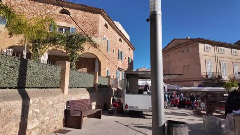 Son-Servera-sunny-morning-square-on-a-market-day-with-vendors-waiting-for-buyers-in-Mallorca,-Spain