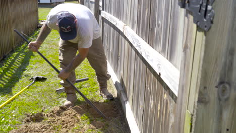 Man-bent-over,-cleaning-out-a-small-hole