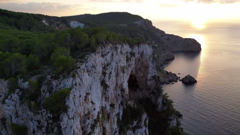 Ibiza-sunset-overlooking-a-rocky-sea-cliff-and-calm-ocean