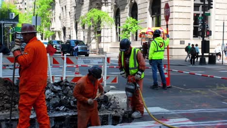 Eine-Aufnahme-Auf-Straßenebene-Von-Männern,-Die-An-Einem-Sonnigen-Tag-Auf-Der-Fifth-Avenue-In-New-York-Einen-Graben-Ausheben