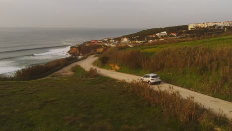 Car-driving-on-coastline-road-during-sunset-light-in-Magoito,-Portugal