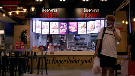 Customers-going-out-of-a-fastfood-restaurant-after-buying-some-food-at-a-shopping-center-located-in-Bangkok,-Thailand