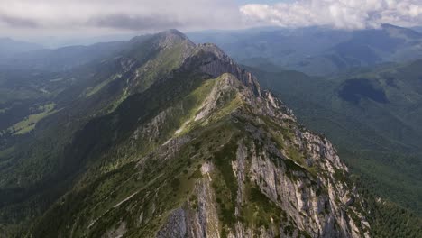 Toma-Aérea-De-La-Cresta-De-Las-Montañas-Piatra-Craiului-Con-Nubes-Que-Proyectan-Sombras-Debajo