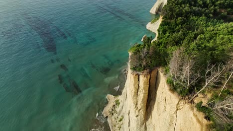 The-sunlit-cliffs-along-the-corfu-island-coastline,-overlooking-the-ionian-sea,-aerial-view