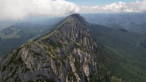 Majestic-aerial-view-of-Piatra-Craiului-Mountains-under-a-cloudy-sky,-lush-valleys-below