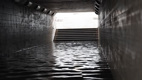 Residents-crossing-a-waterlogged-pedestrian-underpass-after-the-rain-hit-the-UAE-on-May-02,-2024