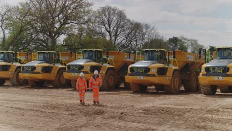 Construction-workers-walk-away-and-discuss-the-inspection-of-a-fleet-of-dump-trucks