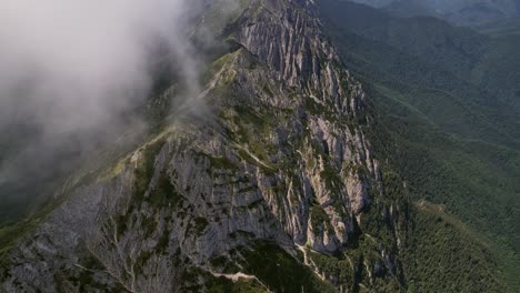 Clouds-swirling-around-the-peaks-of-piatra-craiului-mountains,-aerial-view