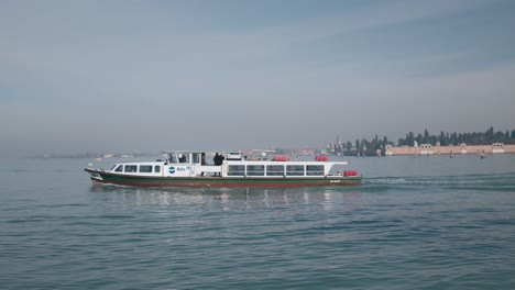 Serene-scene-in-Venice,-Italy,-featuring-a-local-ACTV-vaporetto-boat-cruising-the-calm-waters