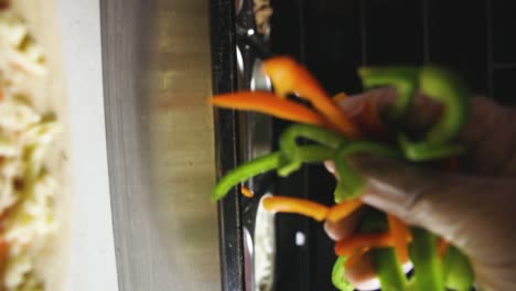 Dropping-sliced-bell-peppers-onto-pizza-Vertical-Shot