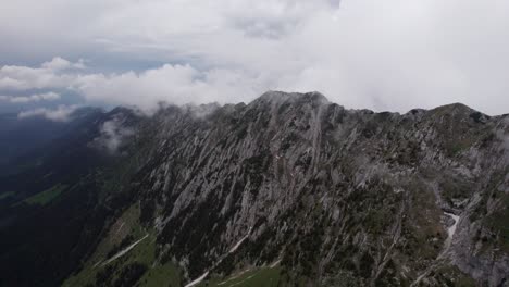 Misty-clouds-enshroud-the-rugged-peaks-of-Piatra-Craiului-Mountains,-aerial-view