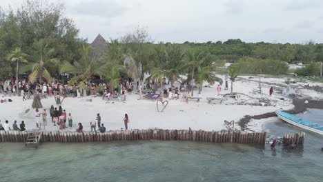 Vista-Aérea-En-Plataforma-Rodante-A-Través-De-La-Concurrida-Playa-De-Michamvi-Kae-Con-Gente-Viendo-El-Espectáculo-De-Baile-De-Zanzíbar