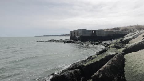 Old-war-time-bunker-and-ocean-lookout-on-the-rocky-shores-of-the-Atlantic-Ocean-in-Portland-Maine-during-a-overcast-day-in-4k