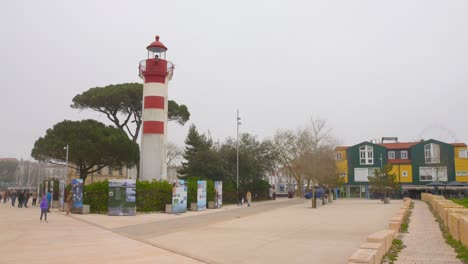 Shot-of-Red-and-white-lighthouse-in-the-historic-"Vieux-Port"-in-La-Rochelle,-France-with-visitors