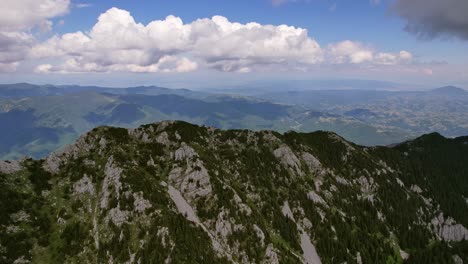 Mountain-peaks-under-a-cloudy-sky-in-Piatra-Craiului,-aerial-view