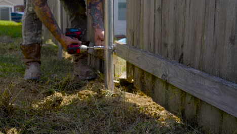 Contractor-bent-over-fixing-privacy-fence.-Jib-down