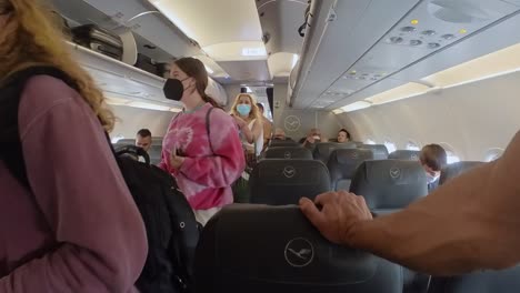 Personas-De-Vacaciones-Abordando-La-Cabina-Del-Avión-Usando-Máscara-Durante-La-Pandemia-De-Covid