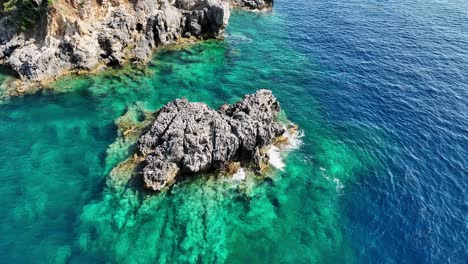 Aerial-shot-of-rugged-cliffs-on-Corfu-Island,-vibrant-turquoise-Ionian-Sea-waters