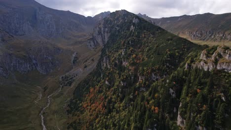 Autumn-colors-drape-the-rugged-Bucegi-Mountains-in-a-vibrant-quilt,-aerial-view-at-dawn