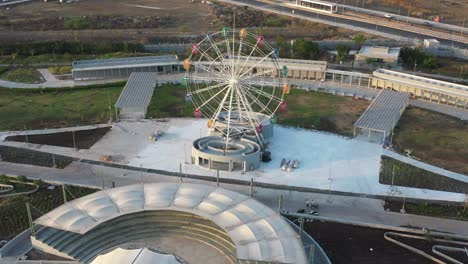 Ein-Sehr-Großes-Riesenrad-Ist-Im-Bereich-Neben-Dem-See-Sichtbar,-Wo-Sich-Die-Drohnenkamera-Vorwärts-Bewegt