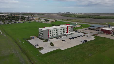 Cayendo-Y-Cerrándose-En-Vista-De-Drones-De-Un-Hotel-ávido-Recientemente-Construido-Con-Molinos-De-Viento-En-El-Fondo