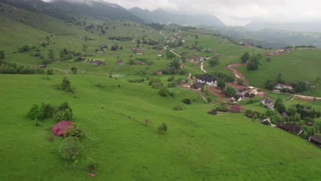 Un-Pueblo-Verde-Y-Exuberante-Con-Superficies-Mojadas-Que-Insinúan-Lluvia-Reciente,-Cielos-Nublados,-Durante-El-Día,-Vista-Aérea