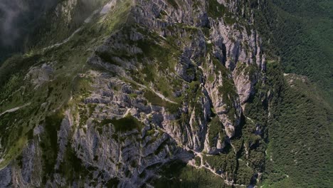 Piatra-craiului-mountains-showcasing-rugged-terrain-and-lush-vegetation,-daylight,-aerial-view