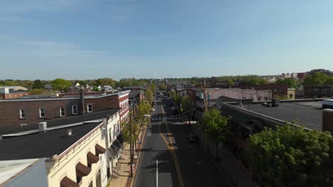 Luftaufnahme-Eines-Einflugs-über-Der-Hauptstraße-Einer-Kleinen-Amerikanischen-Stadt-Bei-Sonnenuntergang