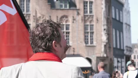 A-man-stands-confidently-in-front-of-a-group-of-red-flags,-symbolizing-solidarity-and-unity