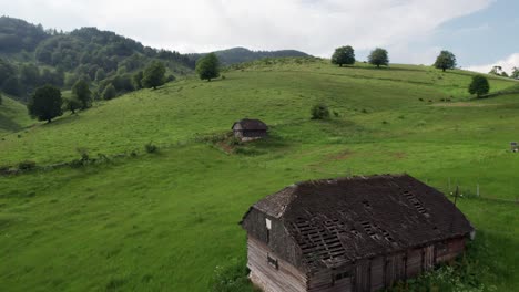 Sirnea-village-with-traditional-houses-among-green-hills,-sunny-day,-aerial-view