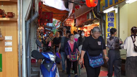 Slow-motion-shot-capturing-people-strolling-through-narrow-laneway-lined-with-food-stalls-and-souvenir-shops,-exploring-Jiufen-Old-Street-of-mountain-town,-popular-tourist-attraction-of-Taiwan