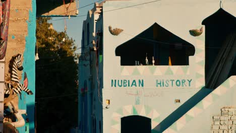 Colorida-Casa-Tradicional-De-Pueblo-Nubio-Con-Pintura-De-&quot;historia-Nubain&quot;-En-La-Pared,-Asuán,-Egipto