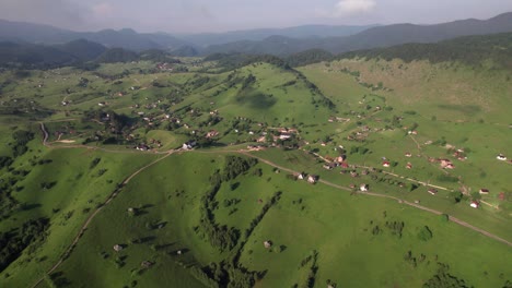 Pueblo-De-Sirnea-En-Rumania-Con-Exuberantes-Colinas-Verdes-Y-Casas-Dispersas,-Día-Soleado,-Vista-Aérea